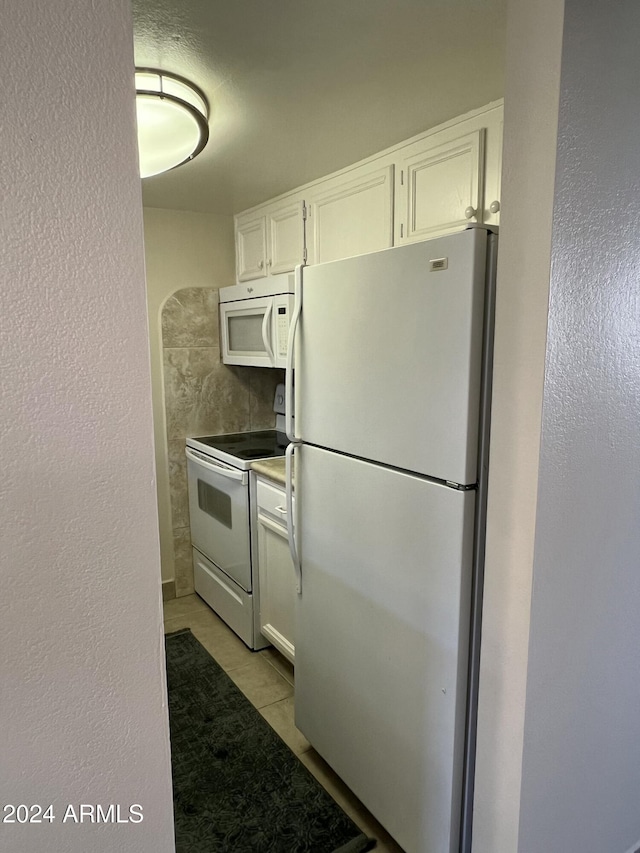 kitchen featuring light tile patterned floors, white cabinets, and white appliances