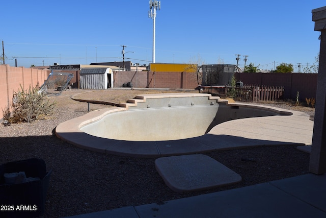 view of yard featuring a storage unit, a patio area, and an empty pool