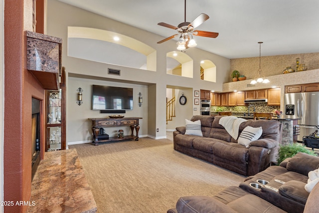 living room with ceiling fan, high vaulted ceiling, and light carpet