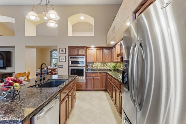 kitchen with sink, stainless steel appliances, backsplash, pendant lighting, and dark stone counters