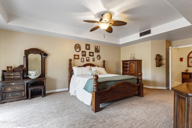 bedroom with a raised ceiling, ceiling fan, and light colored carpet