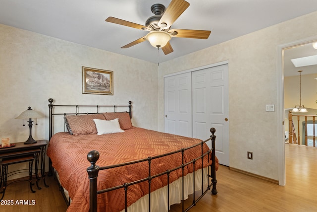 bedroom featuring ceiling fan with notable chandelier, a closet, and light hardwood / wood-style flooring