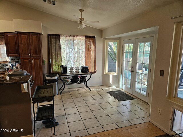 kitchen featuring stainless steel appliances, dark stone counters, light tile patterned floors, and backsplash