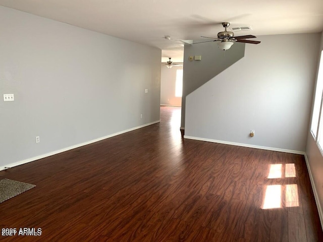 empty room featuring a wealth of natural light, dark hardwood / wood-style flooring, and ceiling fan