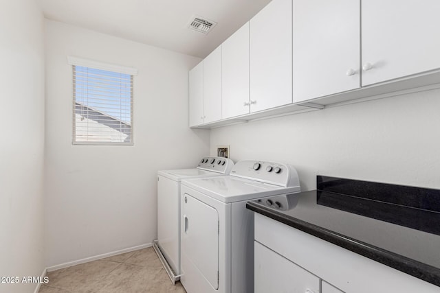 laundry area with light tile patterned floors, washing machine and dryer, and cabinets