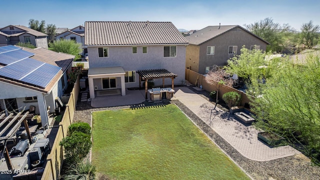 back of property with solar panels, a patio, a pergola, and a lawn