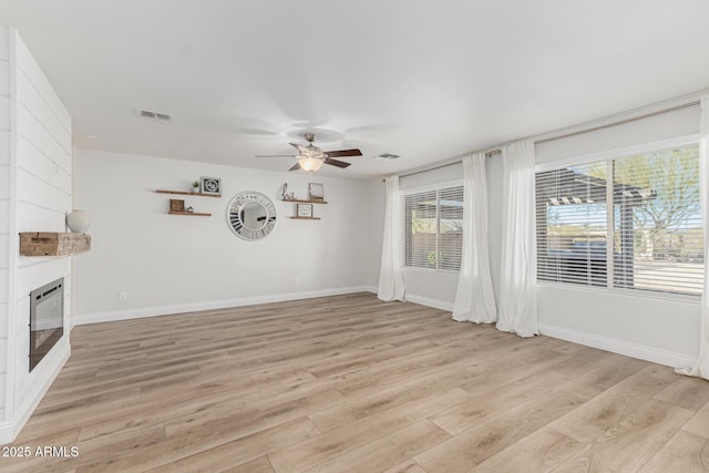 unfurnished living room featuring ceiling fan, light wood-type flooring, and a fireplace