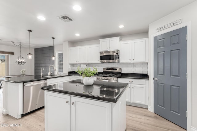 kitchen with white cabinetry, sink, stainless steel appliances, and a kitchen island