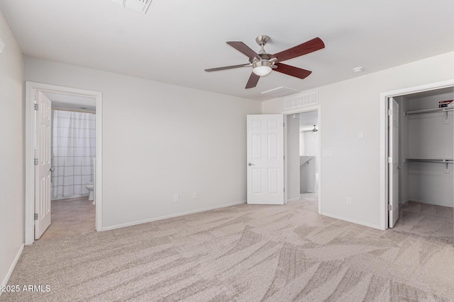 unfurnished bedroom featuring ensuite bathroom, a walk in closet, light colored carpet, ceiling fan, and a closet