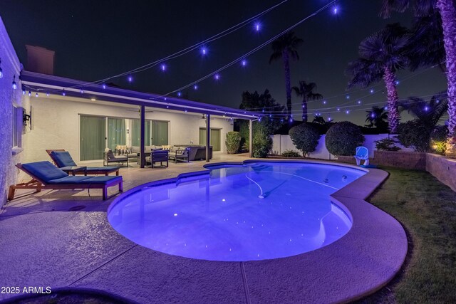 6220 E Paradise Ln, Scottsdale, AZ 85254 - pool at night with an outdoor hangout area, a patio, and a fenced backyard