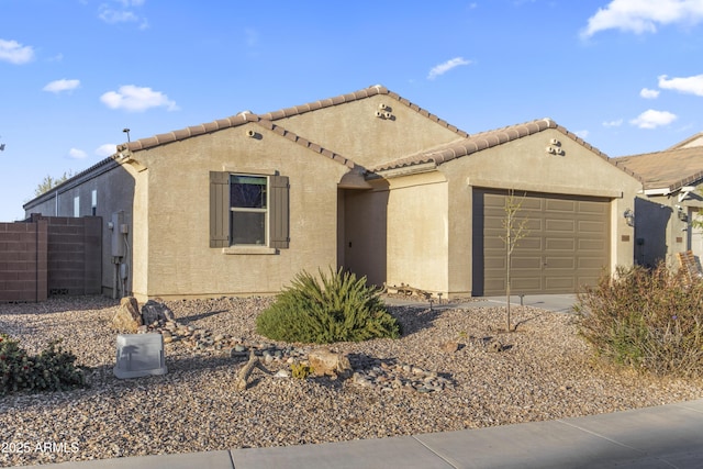 mediterranean / spanish house with an attached garage, a tile roof, fence, and stucco siding