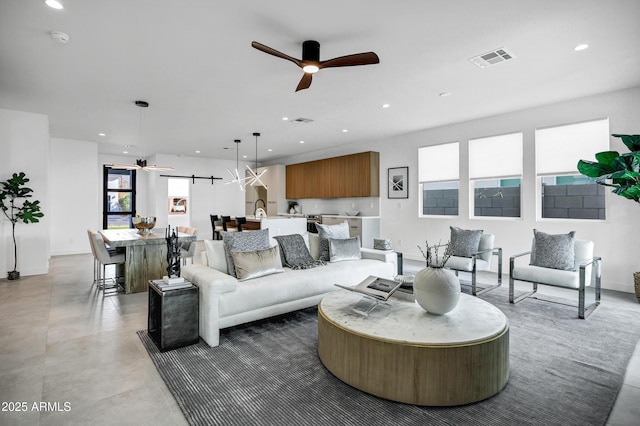 living room featuring ceiling fan and a barn door