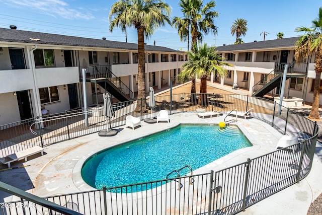 community pool featuring fence, a patio area, and stairway