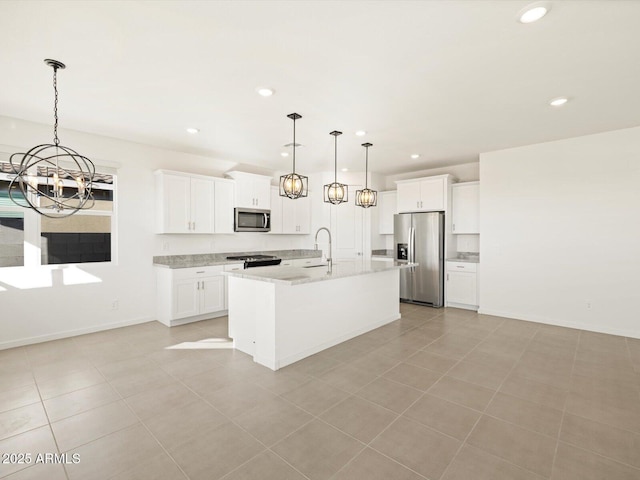 kitchen with appliances with stainless steel finishes, decorative light fixtures, white cabinetry, light stone countertops, and a center island with sink