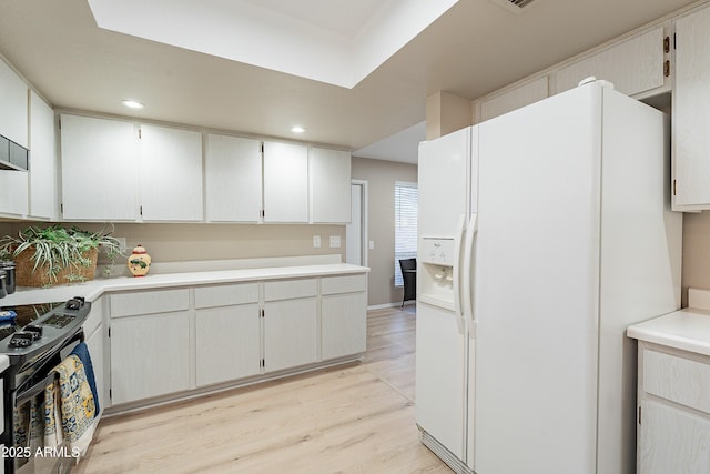 kitchen with white cabinetry, white fridge with ice dispenser, light wood-type flooring, and black / electric stove