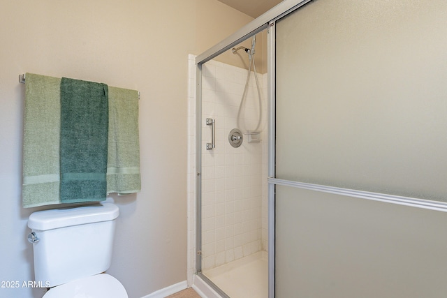 bathroom featuring toilet and a shower with shower door