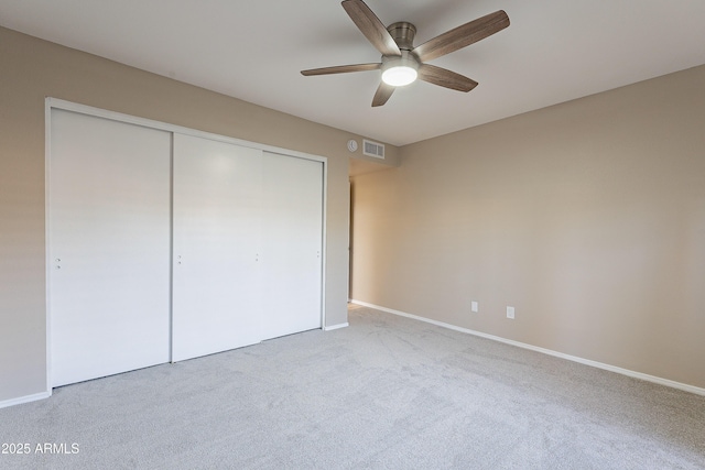 unfurnished bedroom with ceiling fan, light colored carpet, and a closet