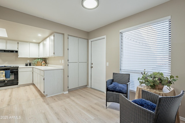 kitchen featuring white cabinetry, black / electric stove, and light hardwood / wood-style flooring