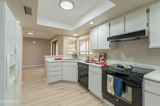 kitchen featuring white cabinetry, sink, light hardwood / wood-style floors, black appliances, and a raised ceiling