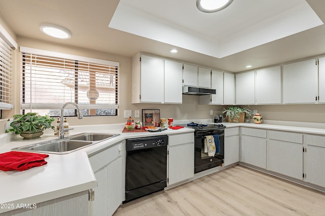 kitchen with sink, light hardwood / wood-style flooring, white cabinetry, a tray ceiling, and black appliances