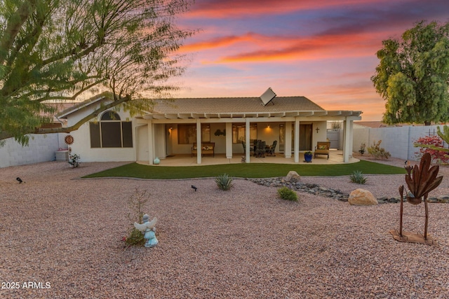 back house at dusk featuring a patio