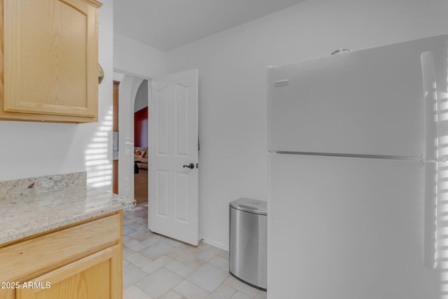 kitchen with light brown cabinetry and white refrigerator