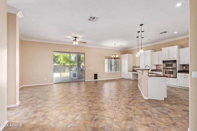 kitchen with stainless steel double oven, an island with sink, a breakfast bar, decorative light fixtures, and white cabinetry