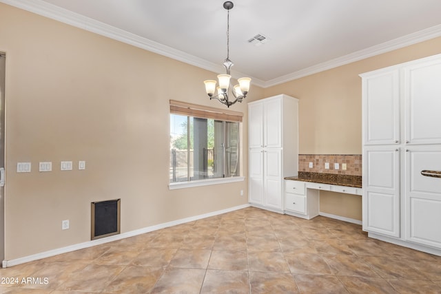 interior space with built in desk, hanging light fixtures, backsplash, crown molding, and white cabinetry