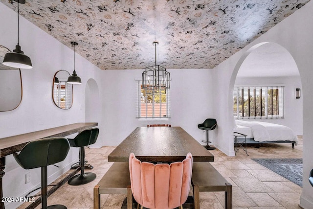 dining area with stone tile flooring, arched walkways, and a healthy amount of sunlight