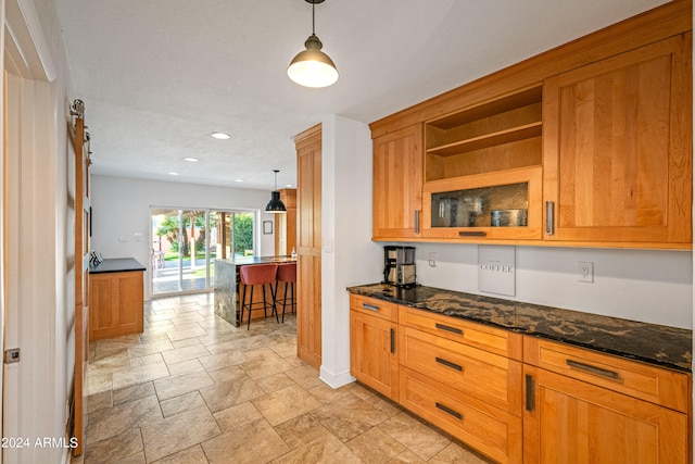 kitchen with dark stone counters, open shelves, brown cabinets, stone finish flooring, and recessed lighting
