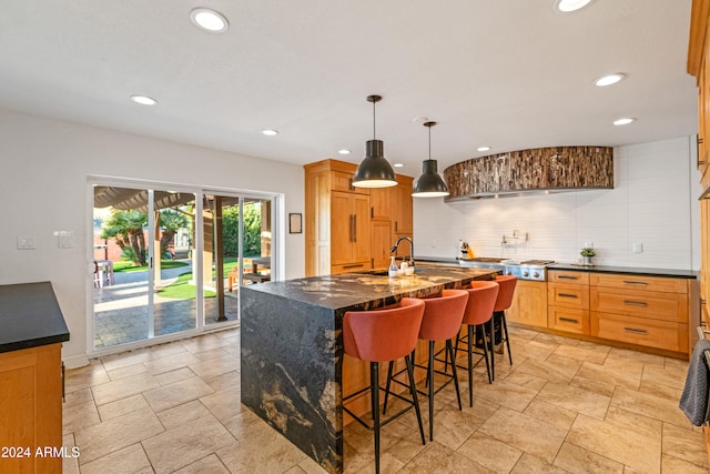 kitchen featuring stainless steel gas cooktop, a breakfast bar, a center island with sink, backsplash, and recessed lighting