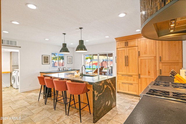 kitchen featuring under cabinet range hood, independent washer and dryer, recessed lighting, and dark stone counters