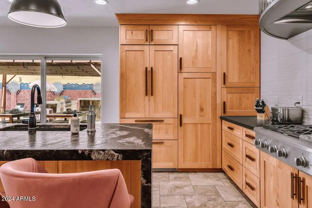 kitchen with a sink, dark countertops, recessed lighting, stainless steel gas stovetop, and stone finish floor