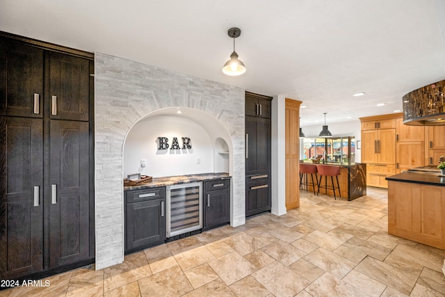 kitchen featuring wine cooler, hanging light fixtures, and dark stone countertops