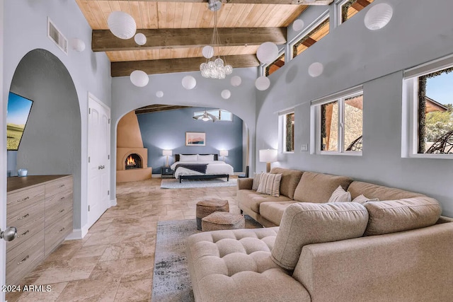 living room featuring stone tile floors, wood ceiling, arched walkways, a notable chandelier, and visible vents