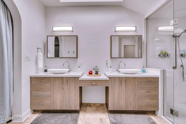 bathroom featuring a shower stall, vaulted ceiling, two vanities, and a sink