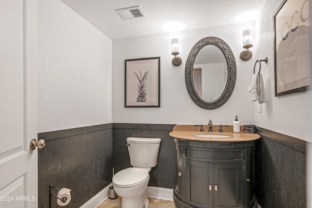 half bath with visible vents, toilet, vanity, and tile patterned floors