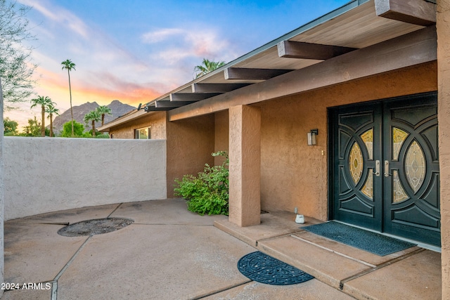 view of exterior entry featuring stucco siding, a patio area, and french doors