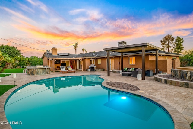 pool at dusk featuring outdoor dry bar, area for grilling, an outdoor pool, an outdoor hangout area, and a patio area