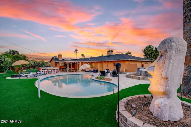 pool at dusk featuring a yard, outdoor dining space, a patio, and an outdoor pool