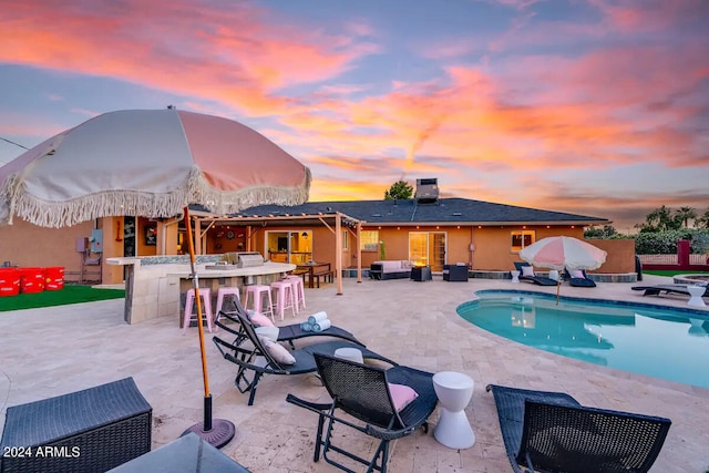 pool at dusk with an outdoor hangout area, a fenced in pool, outdoor dry bar, and a patio