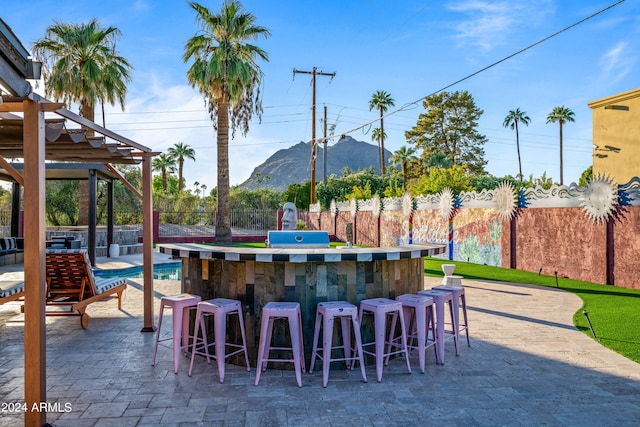 view of patio / terrace with outdoor dry bar, a mountain view, and fence