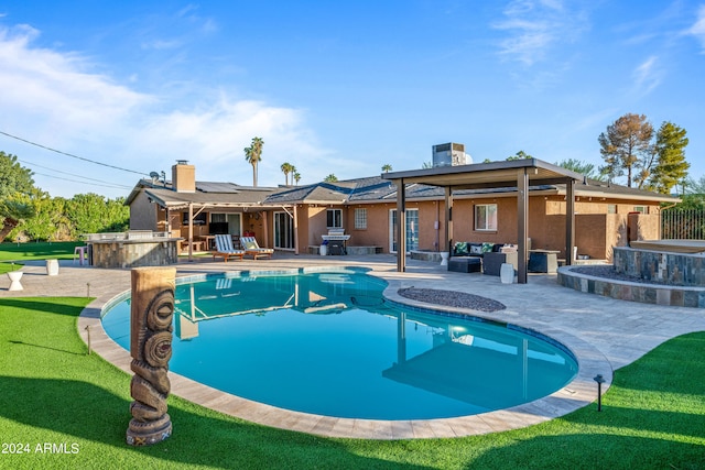 pool with an outdoor living space, a yard, a patio, and exterior kitchen