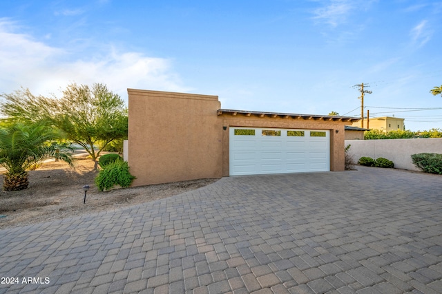 garage featuring decorative driveway and fence