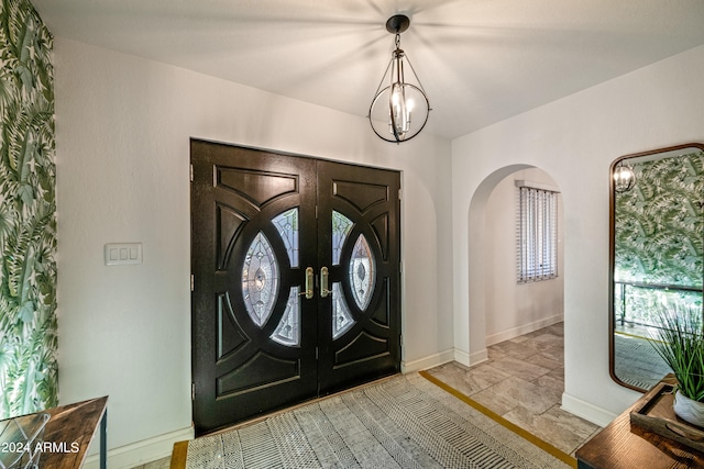 foyer with an inviting chandelier, baseboards, and arched walkways