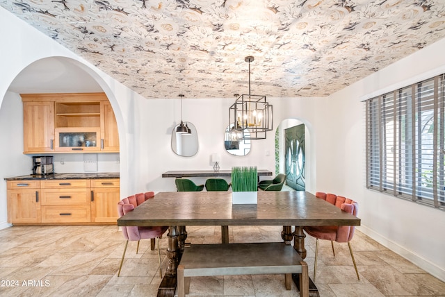 dining room with arched walkways, stone tile floors, an inviting chandelier, and baseboards