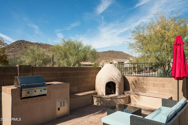 view of patio / terrace with a grill, a mountain view, an outdoor kitchen, and an outdoor fireplace