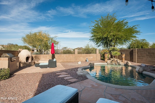 view of swimming pool featuring a patio area, exterior kitchen, and an outdoor fireplace