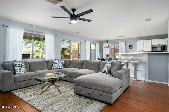 living room with dark hardwood / wood-style flooring and ceiling fan with notable chandelier