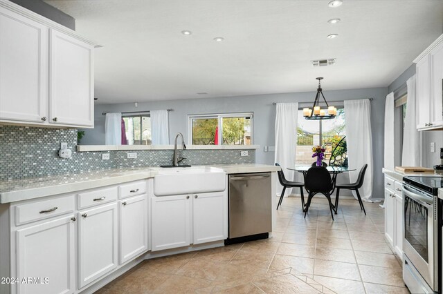 kitchen with hanging light fixtures, sink, decorative backsplash, appliances with stainless steel finishes, and white cabinetry